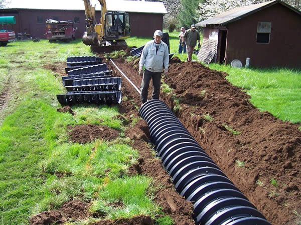 A pressure distribution lateral being installed using graveless chambers in three foot wide trenches.